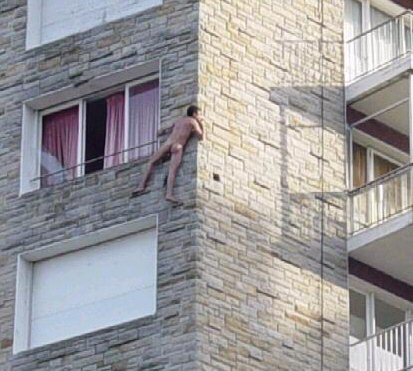 Naked man (Vin) clinging to outside of building